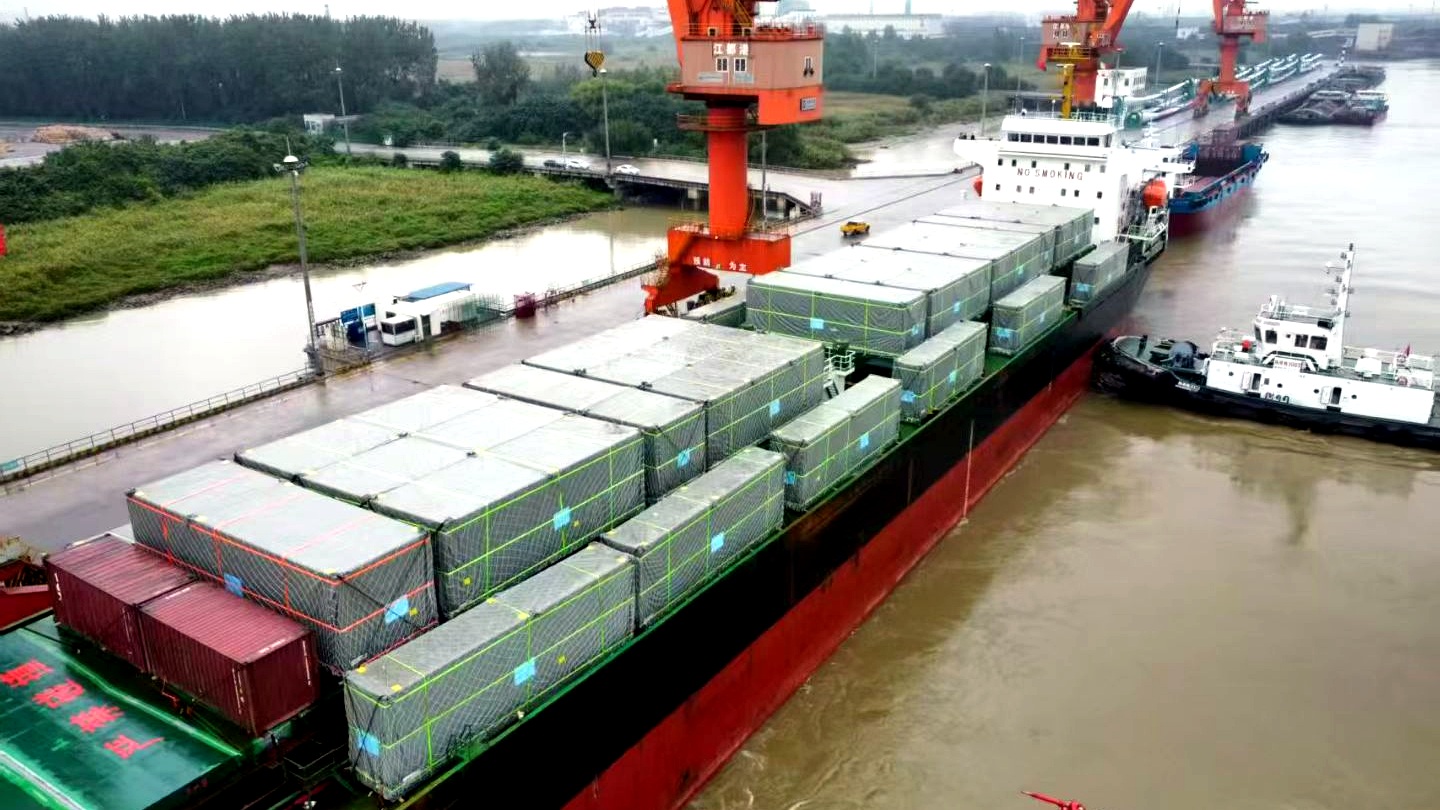 Packaged breakbulk units being loaded onto a vessel at a Chinese port, seen from above